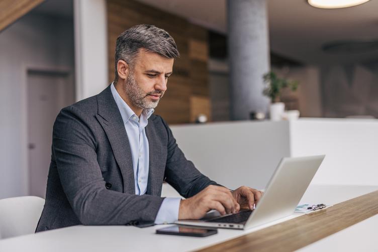 Businessman in suit using laptop at table