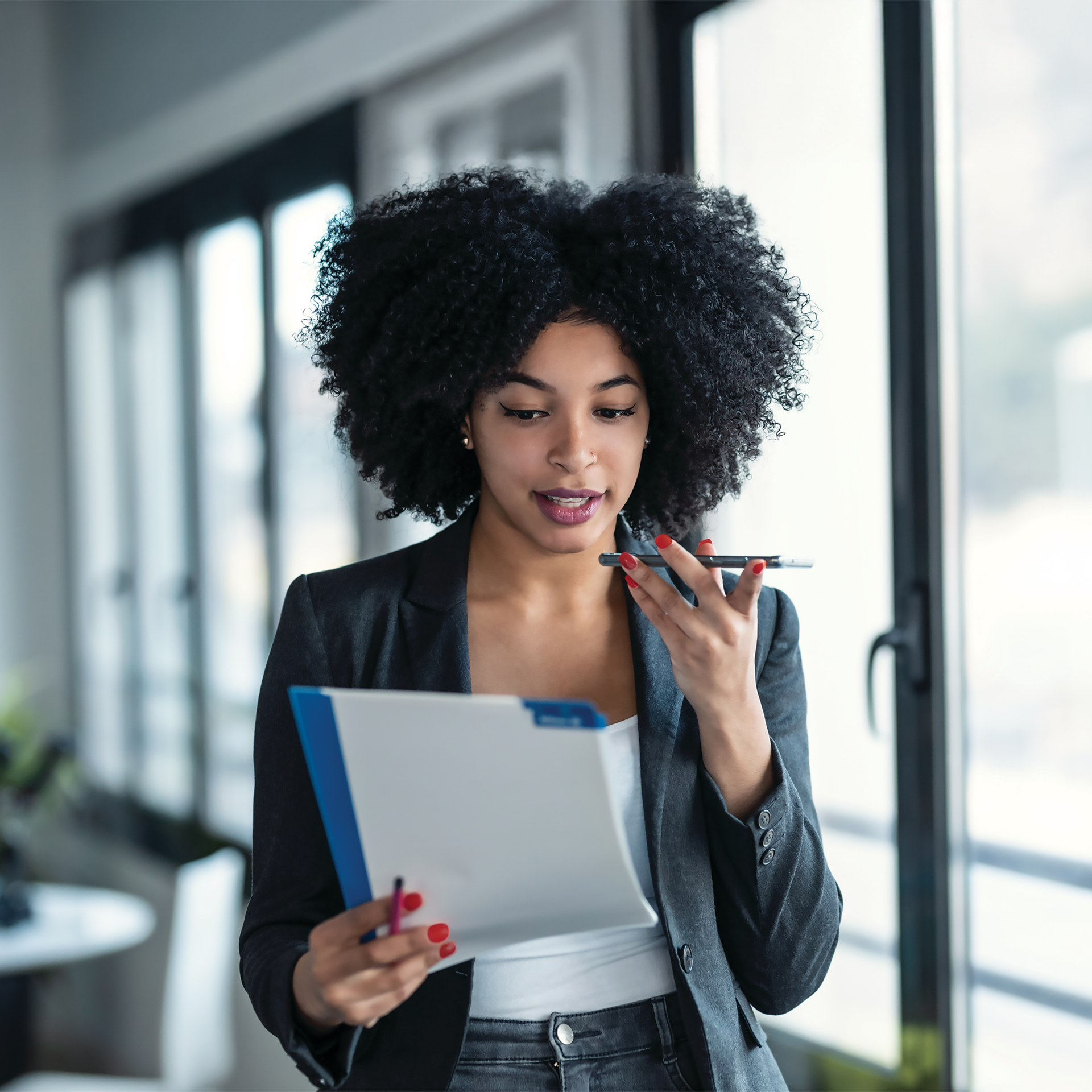 Businesswoman speaking on the phone holding files in her hand
