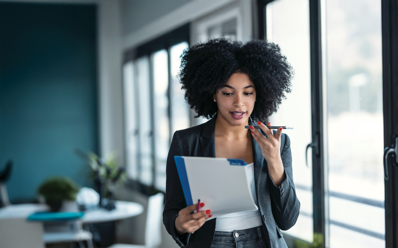 Businesswoman speaking on the phone holding files in her hand