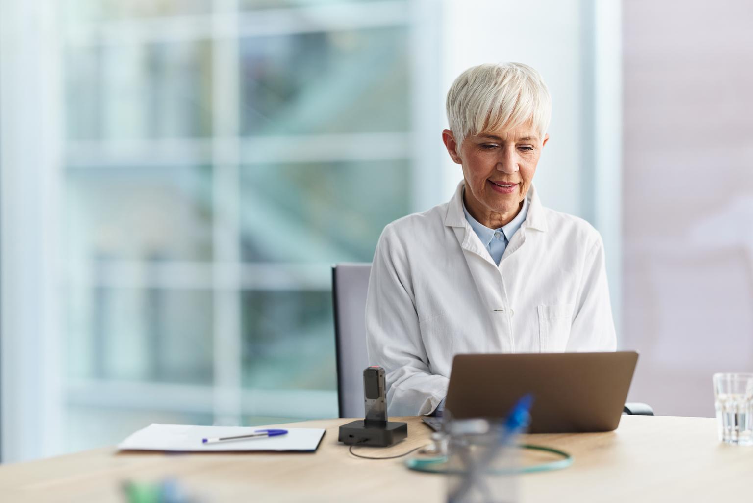 Physician working on laptop while recording with Philips SpeechMike Ambient