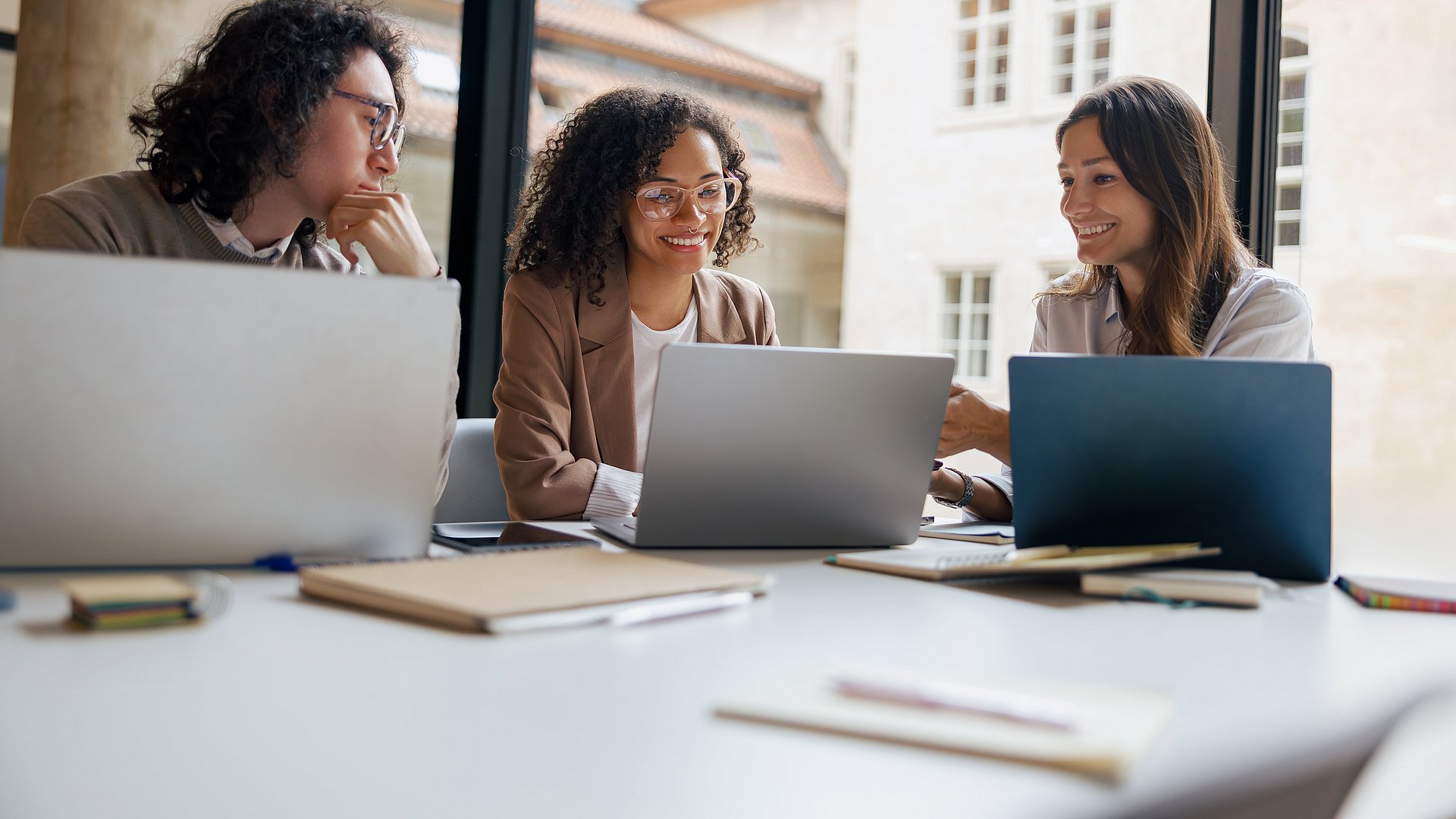 A diverse team collaborates on strategies using laptops in a bright, modern workspace that fosters creativity