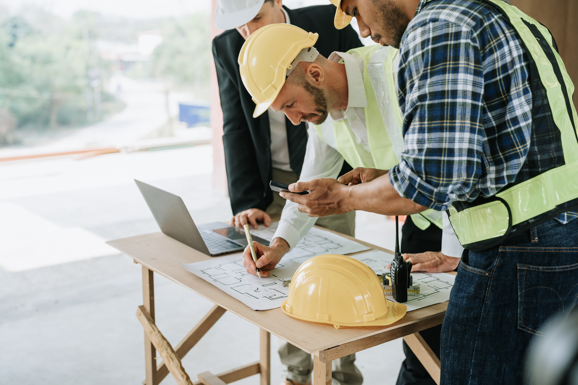 Construction professionals reviewing building plans and using Philips SpeechLive on site.